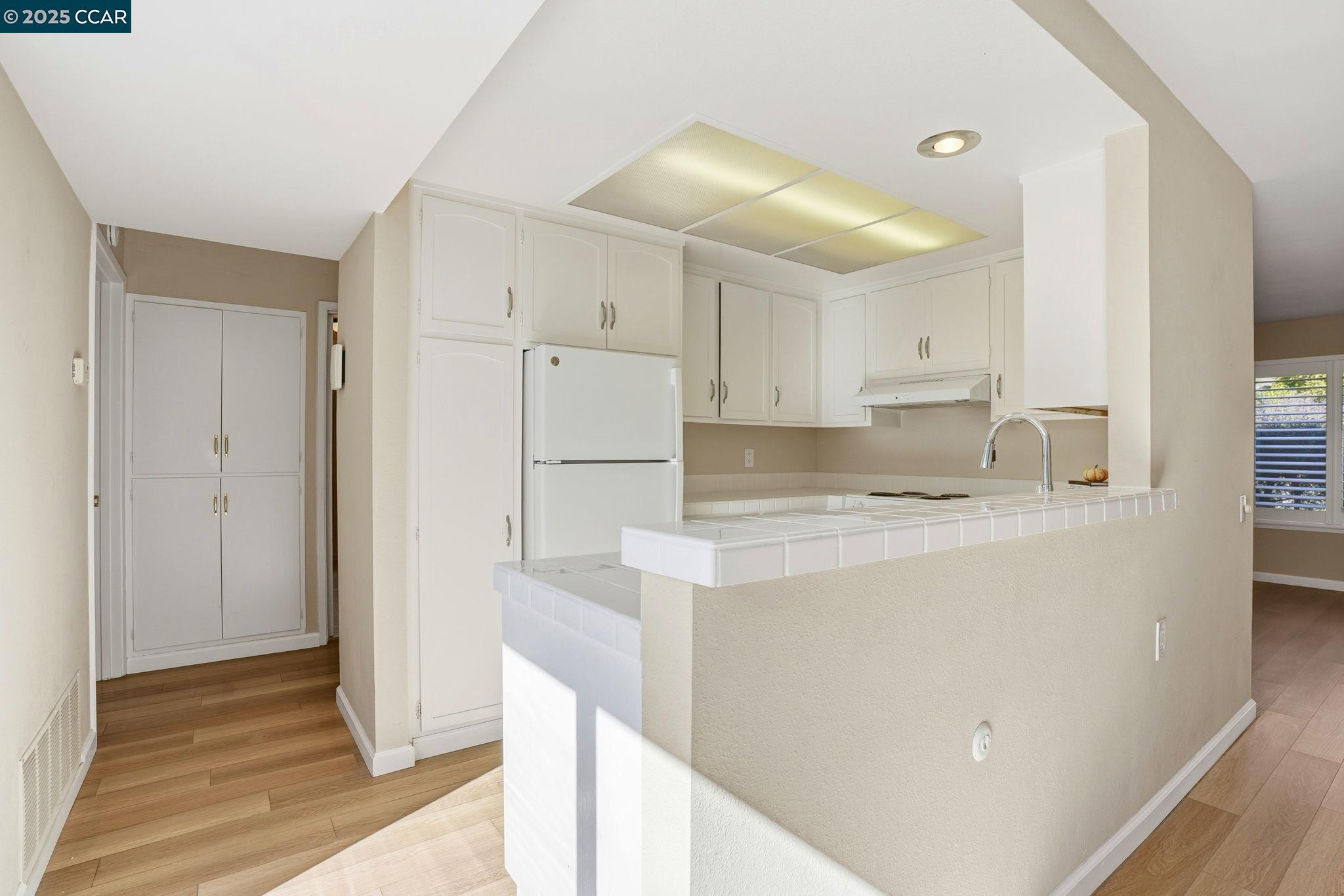 2425 Pine Knoll Drive, Unit 1 Walnut Creek, CA 94595 - Photo 6 of 43 a kitchen with a refrigerator a stove and white cabinets