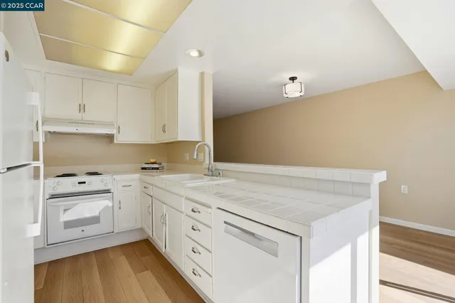 a kitchen with granite countertop white cabinets and white appliances