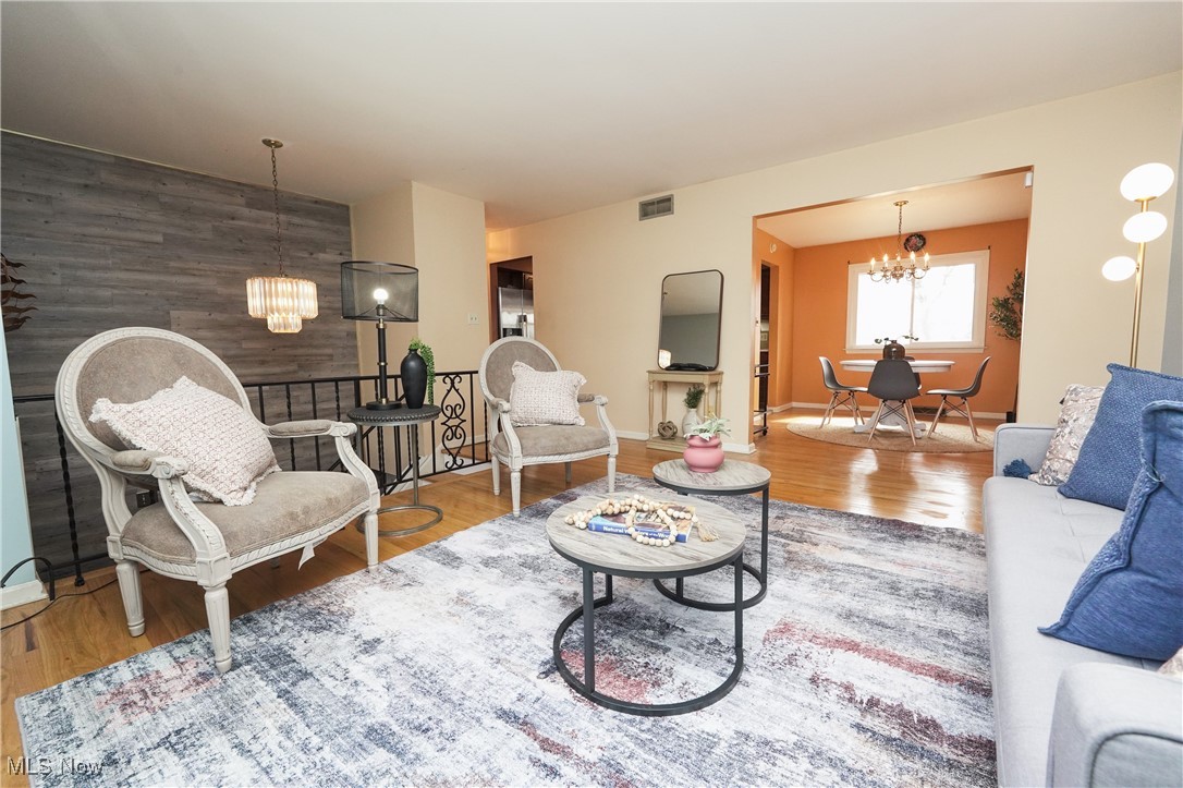2674 Smith Road Fairlawn, OH 44333 - Photo 10 of 31 Living room with an accent wall, wood finished floors, visible vents, and an inviting chandelier
