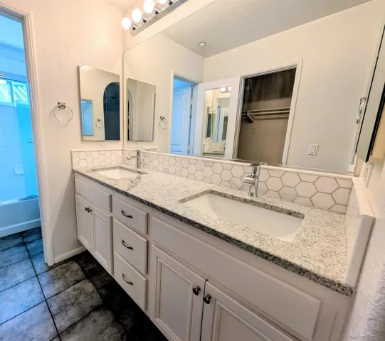 a bathroom with a granite countertop double vanity sink and mirror
