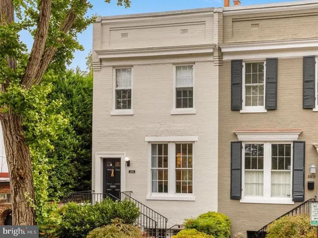 a view of a brick house with large windows and plants