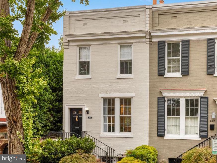 a view of a brick house with large windows and plants