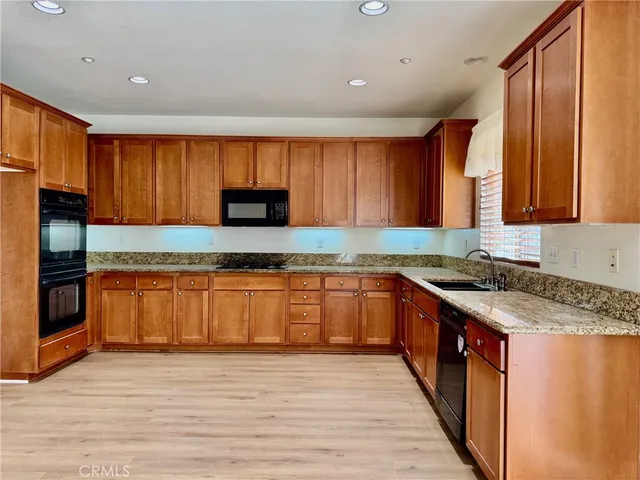 a kitchen with stainless steel appliances granite countertop wooden cabinets a stove top oven a sink and dishwasher