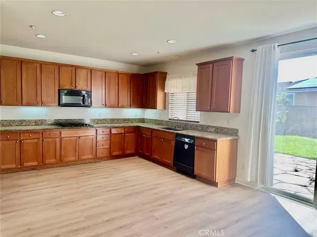 a large kitchen with granite countertop a stove top oven a sink a counter space and cabinets