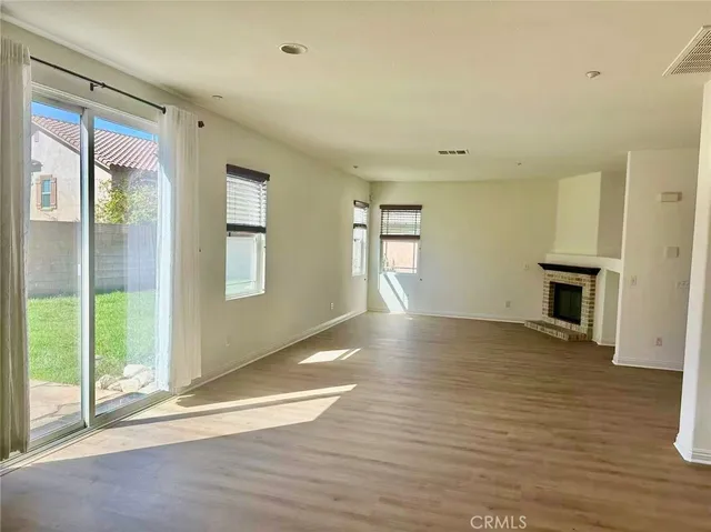 a view of empty room with wooden floor and fireplace