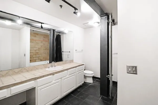 a bathroom with a granite countertop sink mirror vanity and toilet