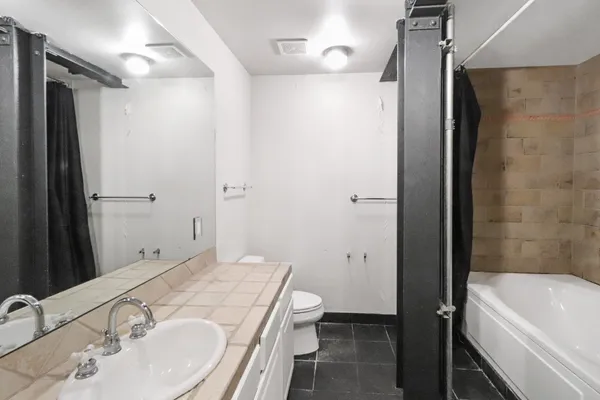 a bathroom with a granite countertop sink toilet and shower