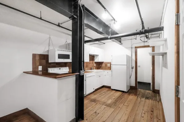 a kitchen with a wooden floor and a refrigerator