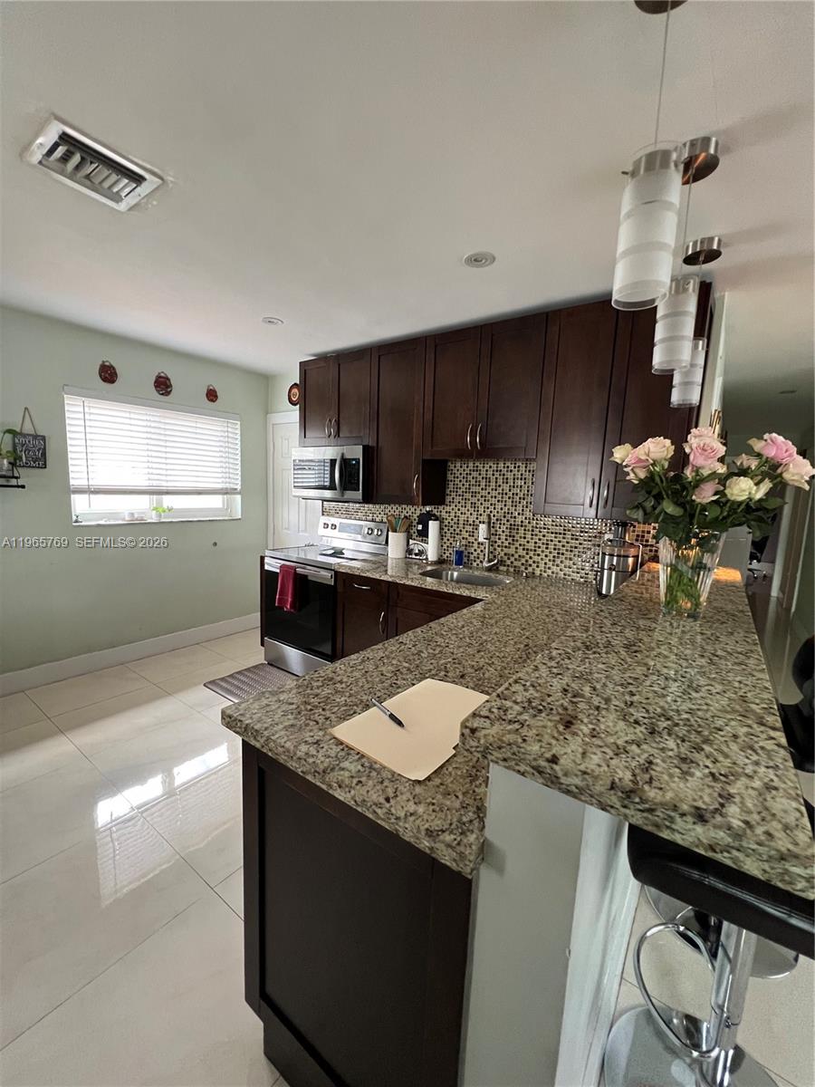 10382 Southwest 25th Street Miami, FL 33165 - Photo 6 of 16 a kitchen with stainless steel appliances granite countertop a sink stove and refrigerator