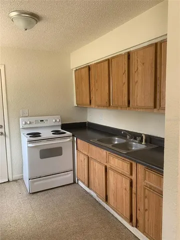 a white kitchen with granite top and stainless steel appliances