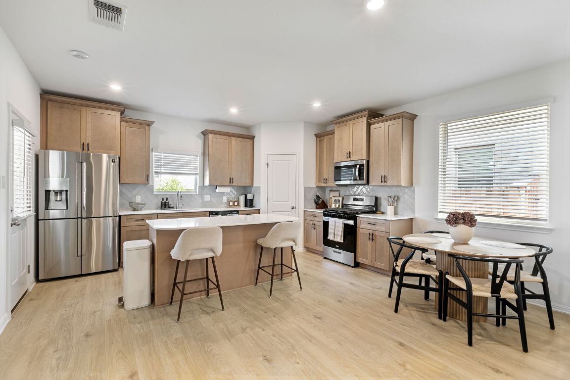 615 Backstays Loop Kyle, TX 78640 - Photo 9 of 36 a kitchen with stainless steel appliances granite countertop a dining table chairs refrigerator and sink