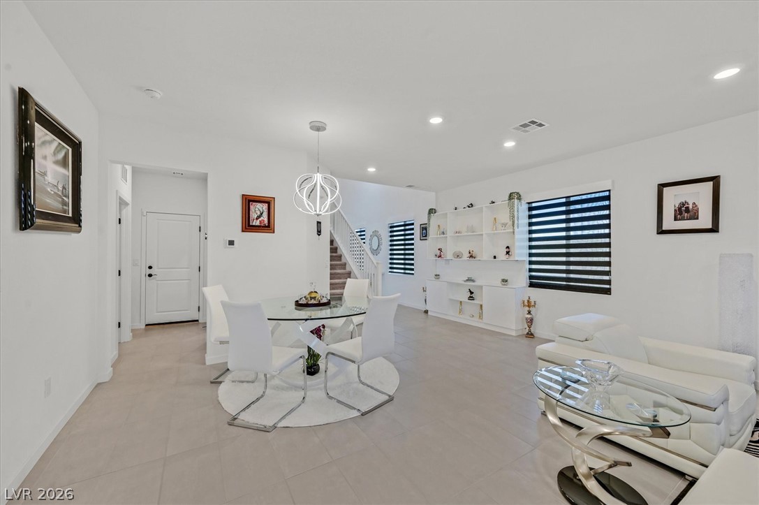 2933 Little Current Road North Las Vegas, NV 89086 - Photo 4 of 35 A graceful chandelier hangs above a dining area, blending seamlessly into an open living space with built-in shelving.