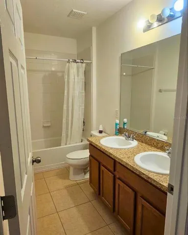 a bathroom with a granite countertop sink toilet a large mirror a shower and a bathtub