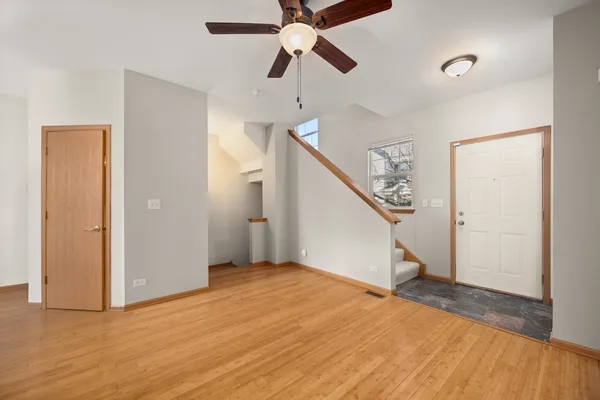 a view of empty room with wooden floor and fan