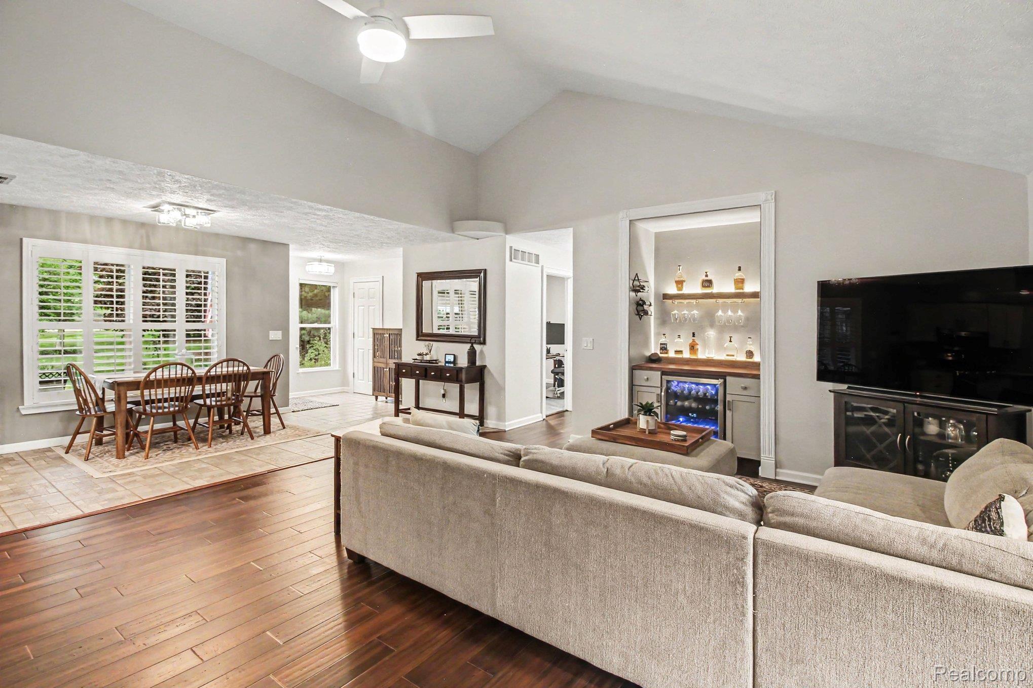 5183 North Owosso Road Fowlerville, MI 48836 - Photo 7 of 27 Living room with ceiling fan, dark wood-style flooring, a bar, lofted ceiling, and wine cooler