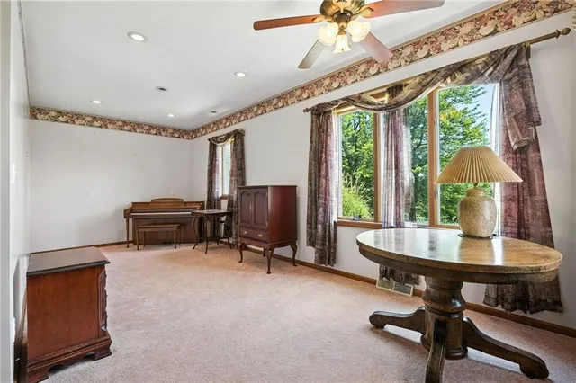 a living room with furniture a ceiling fan and a large window