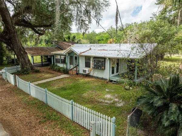 a view of a house with large tree next to a yard