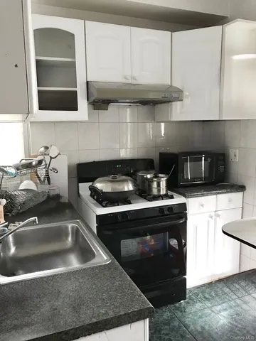a kitchen with granite countertop a sink a stove and cabinets