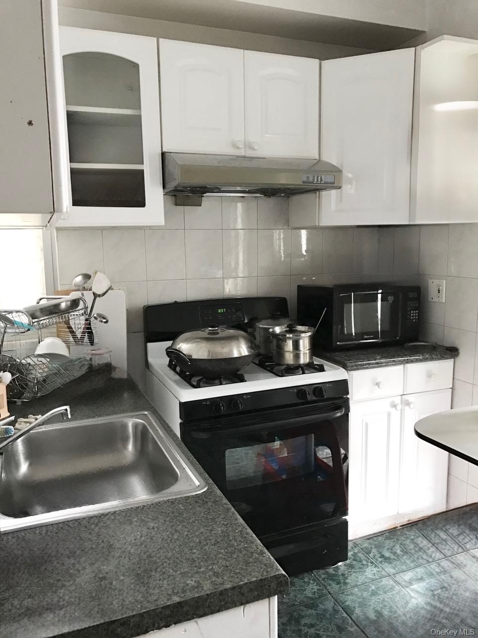98-08 Alstyne Avenue Queens, NY 11368 - Photo 3 of 7 a kitchen with granite countertop a sink a stove and cabinets