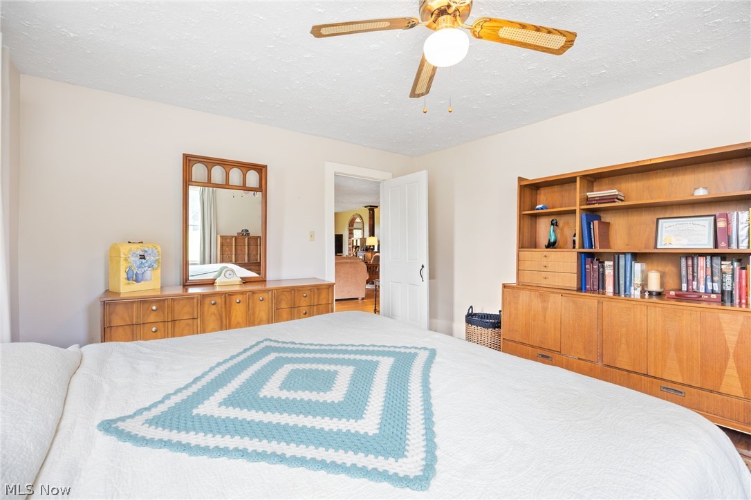 9626 Daniels Road Seville, OH 44273 - Photo 19 of 37 Bedroom featuring a ceiling fan with integrated lighting, a built-in wood-finish shelving unit, and a doorway opening to another interior space
