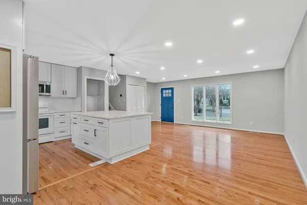 a large kitchen with kitchen island white cabinets and stainless steel appliances