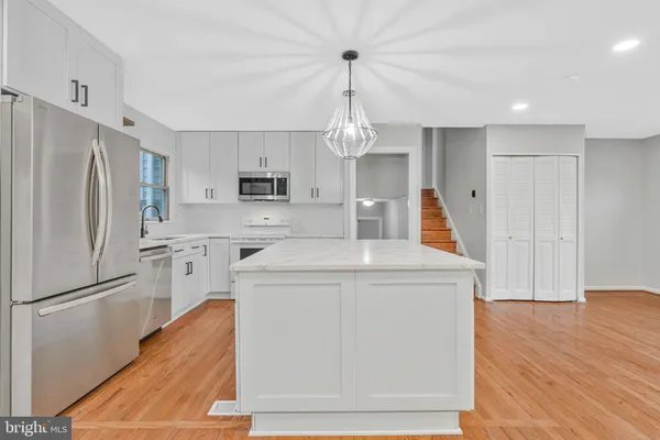 a kitchen with kitchen island white cabinets and stainless steel appliances