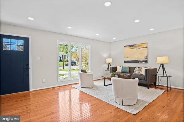 a living room with furniture a large window and wooden floor