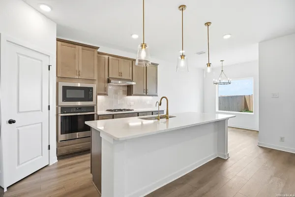 a kitchen with stainless steel appliances granite countertop a sink a oven and a refrigerator with wooden floor