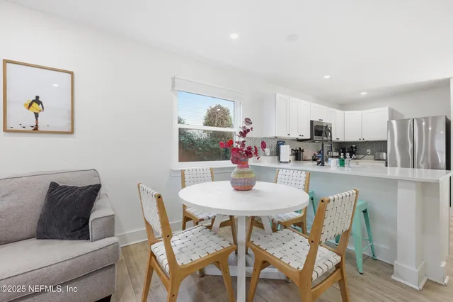 a kitchen with a dining table chairs and refrigerator