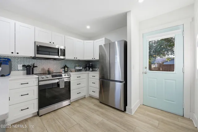 a kitchen with stainless steel appliances white cabinets and a refrigerator