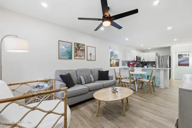 a living room with furniture kitchen view and a wooden floor