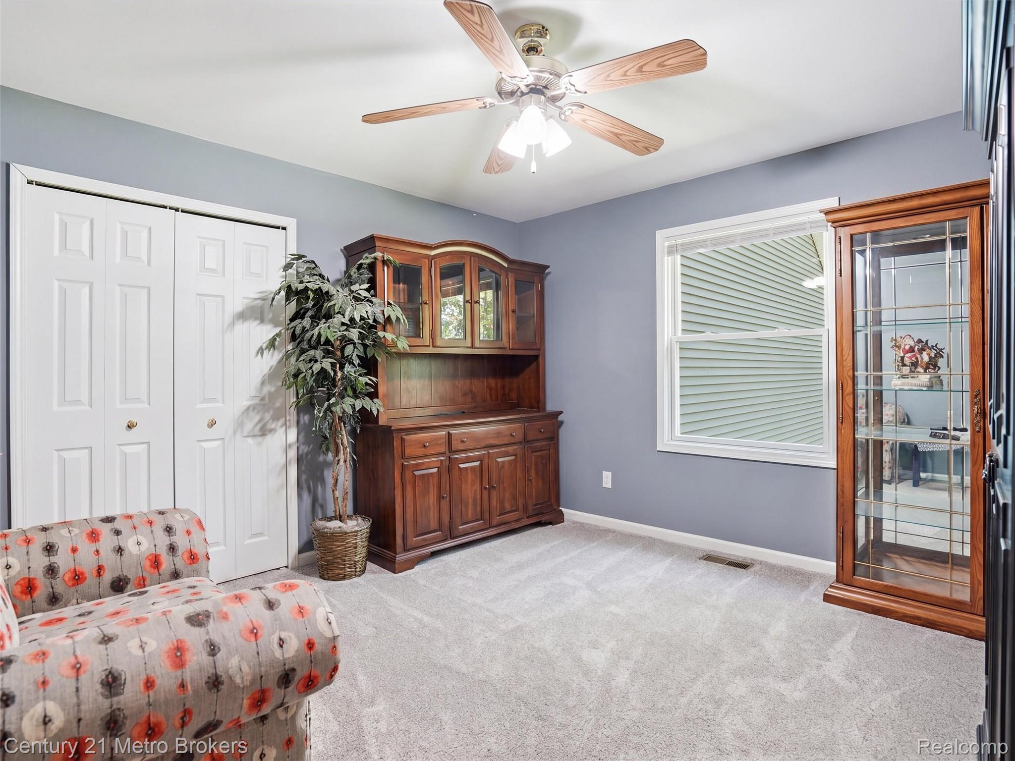 11447 North Latson Road Linden, MI 48451 - Photo 15 of 52 Room featuring light gray carpeting, a single window with white trim, and a ceiling fan with wood-finish blades