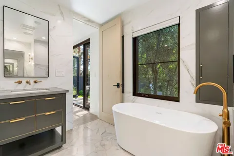 a spacious bathroom with a tub sink and mirror