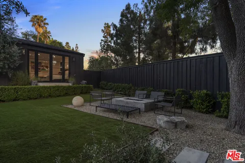 a view of a backyard with couches plants and large tree