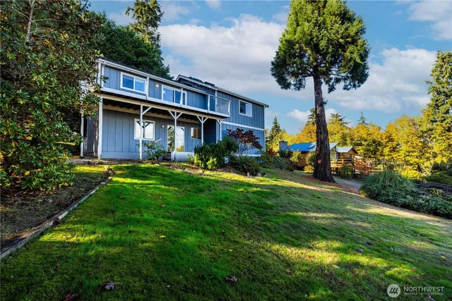 a view of a house with a big yard plants and large trees