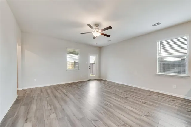an empty room with wooden floor and windows