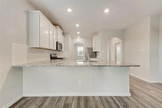 a kitchen with stainless steel appliances granite countertop a sink a stove and cabinets