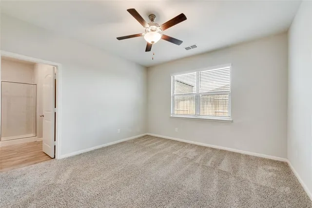 an empty room with windows and ceiling fan