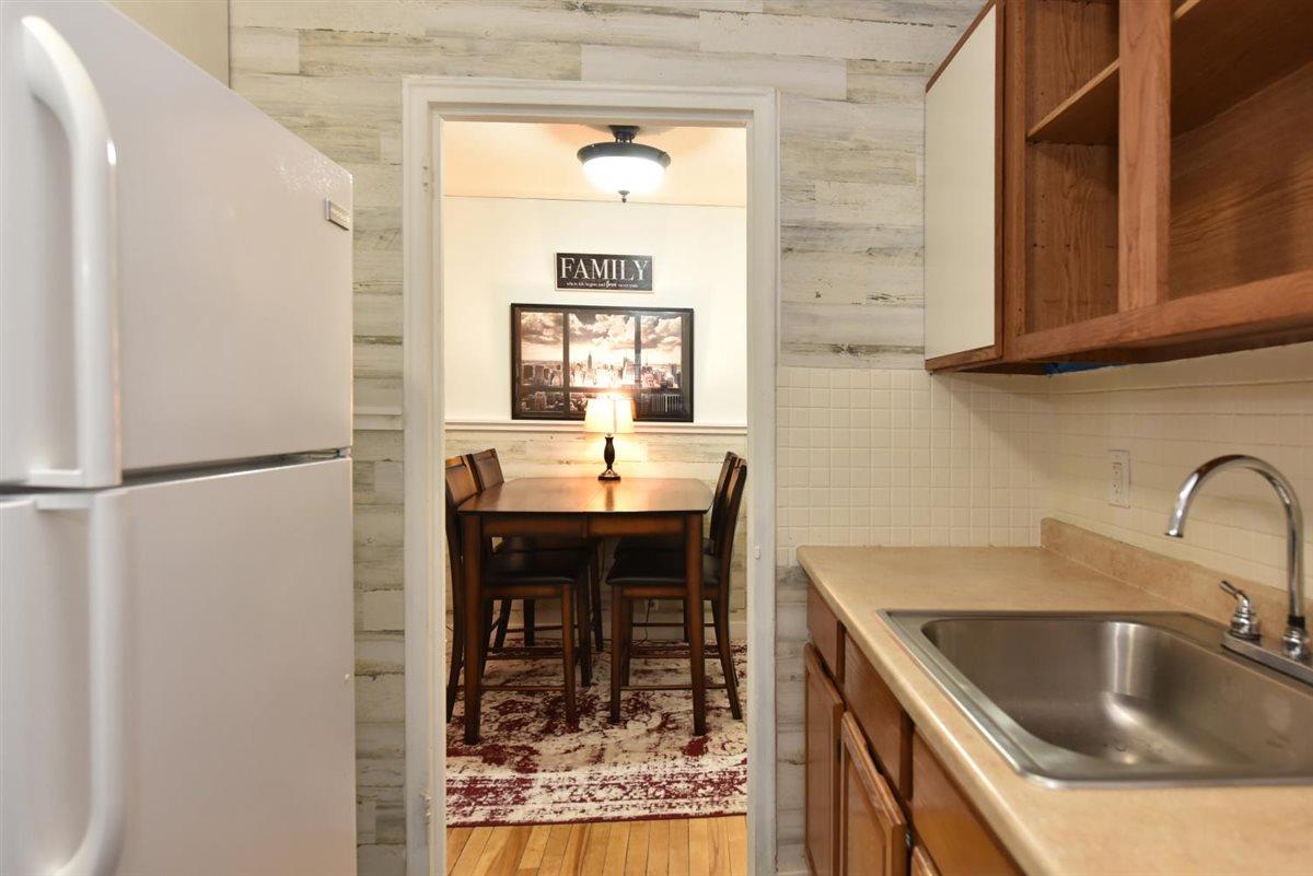 196-65 69th Avenue, Unit 1 Queens, NY 11365 - Photo 15 of 24 Kitchen with a sink, light countertops, freestanding refrigerator, light wood-style floors, and brown cabinets