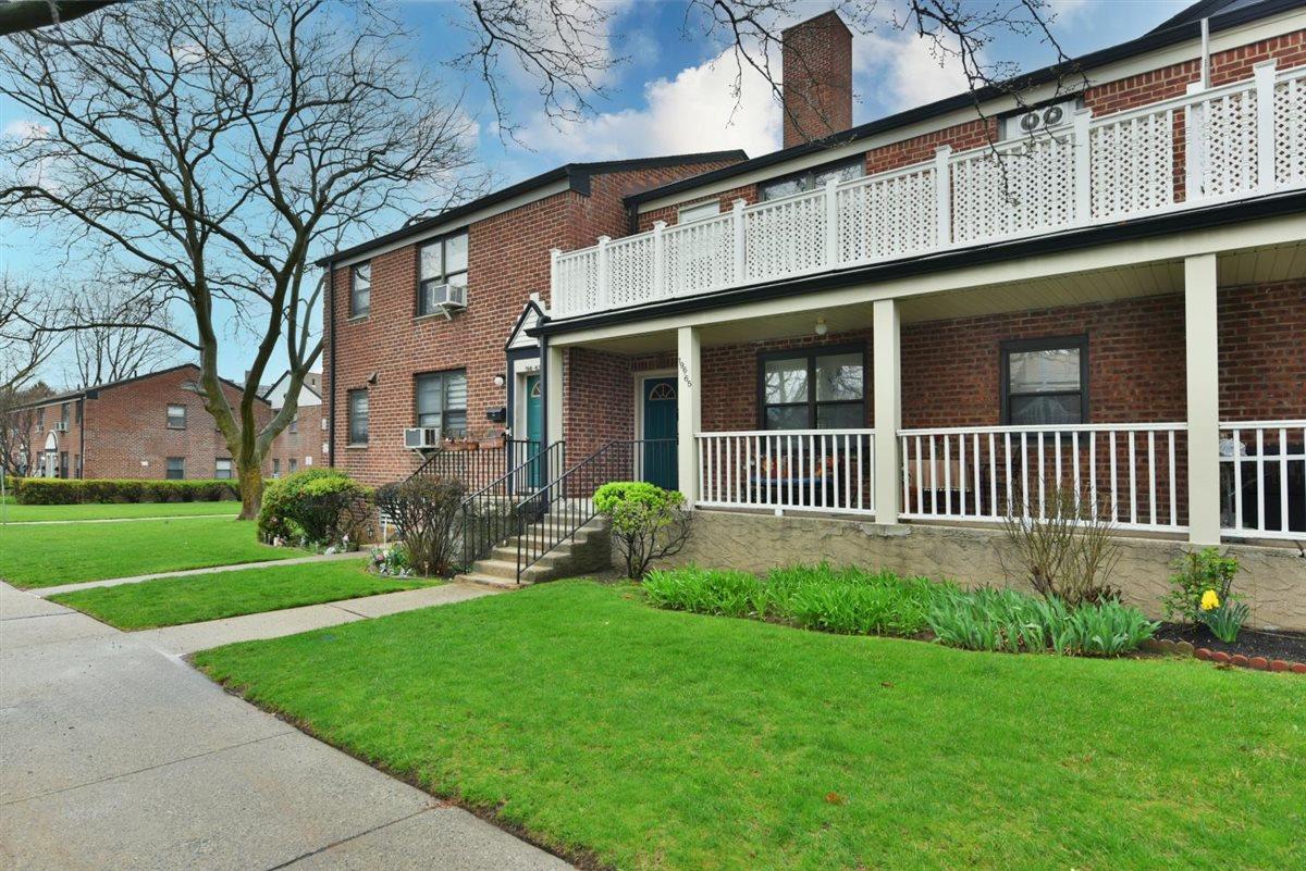 196-65 69th Avenue, Unit 1 Queens, NY 11365 - Photo 2 of 24 View of front of house featuring a porch, brick siding, a front yard, a balcony, and a chimney