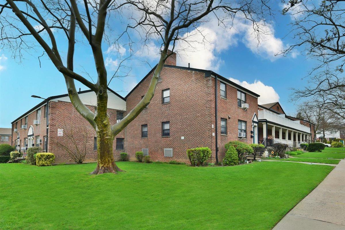 196-65 69th Avenue, Unit 1 Queens, NY 11365 - Photo 22 of 24 View of side of home with a chimney, a residential view, and a lawn