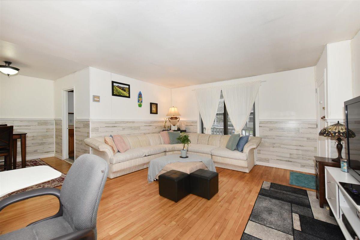 196-65 69th Avenue, Unit 1 Queens, NY 11365 - Photo 7 of 24 Living room with wood walls, light wood finished floors, and wainscoting