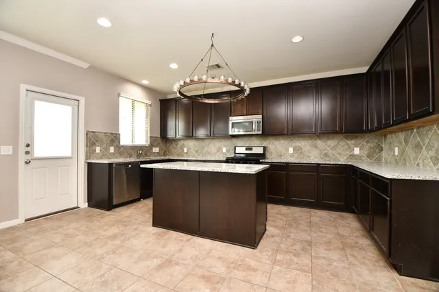 a kitchen with granite countertop stainless steel appliances a sink stove and cabinets