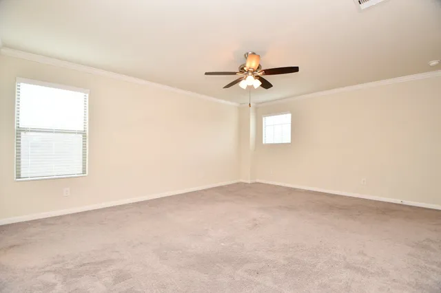 an empty room with windows and fan