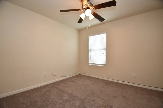 an empty room with a window and a fan