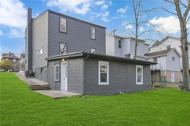 a brick house that has a small yard and a large tree