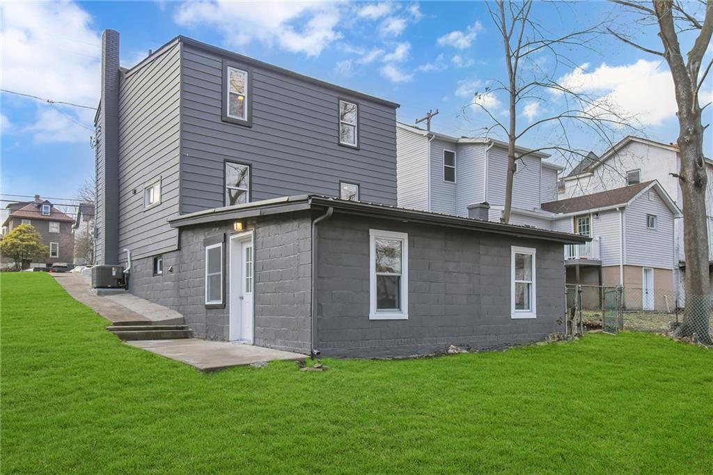 517 Adams Street Rochester, PA 15074 - Photo 4 of 21 a brick house that has a small yard and a large tree