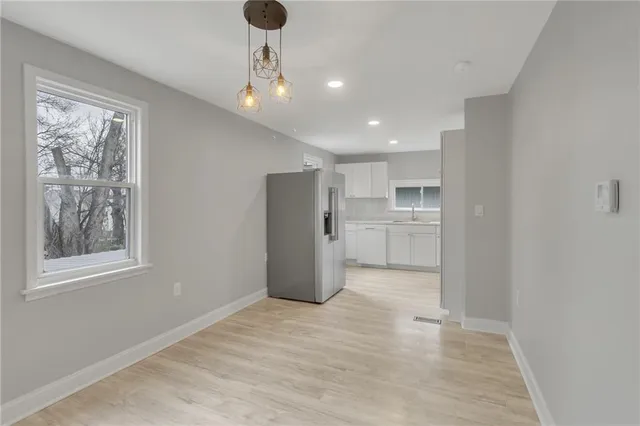 a view of a kitchen with a fridge and wooden floor