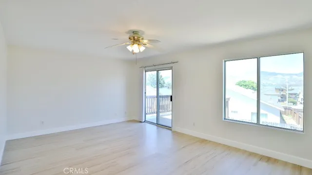 a view of an empty room with a window and wooden floor