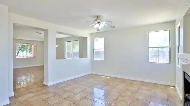 a view of an empty room with window and chandelier fan